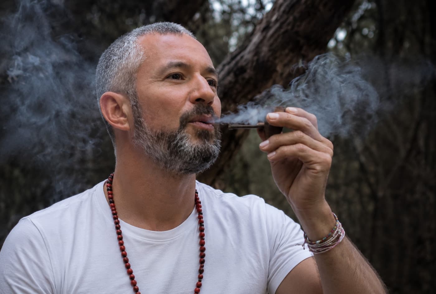 Ameyalli holding a smoking ceremonial pipe outdoors